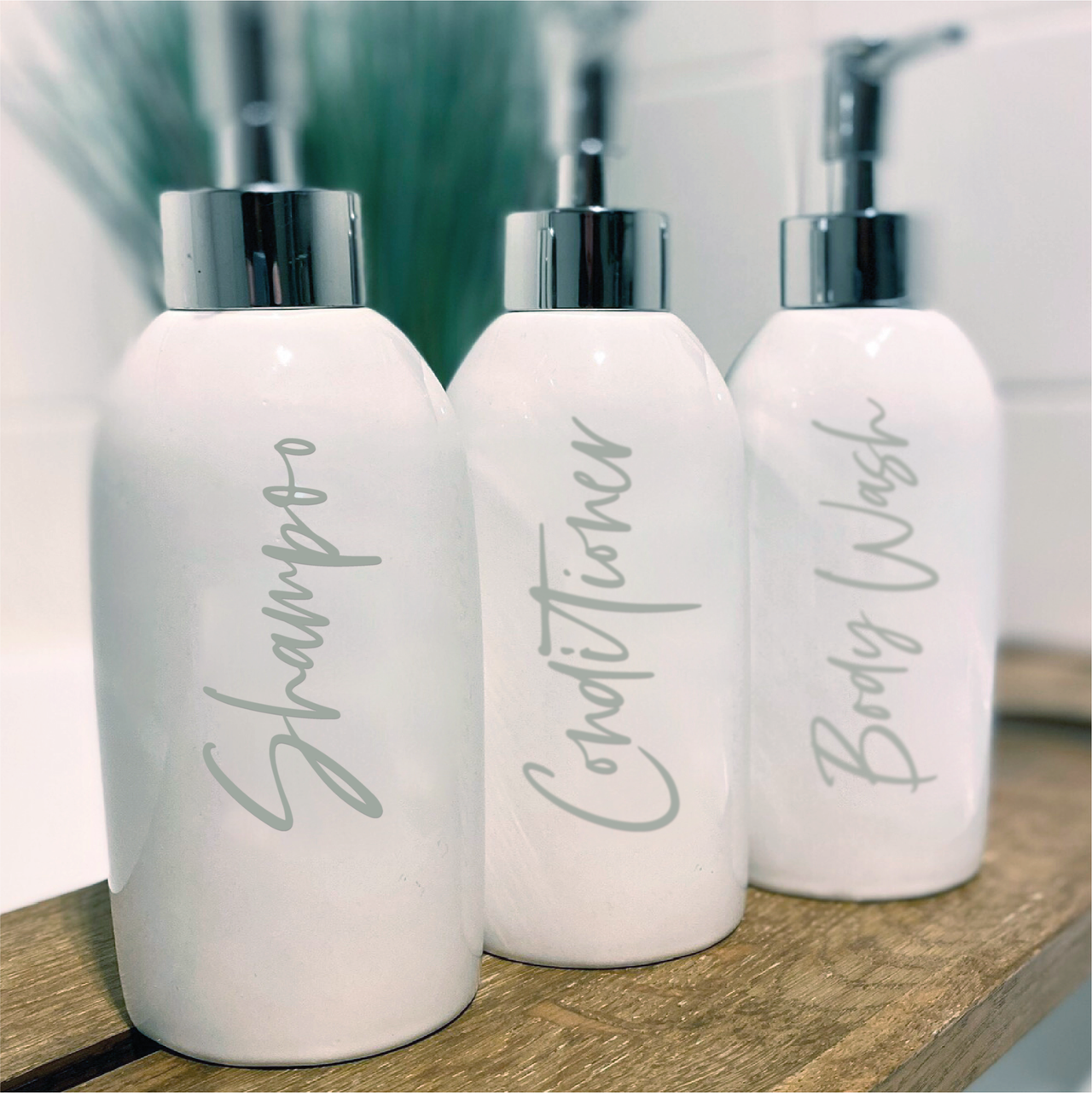 Three white pump bottles with Shampoo, Conditioner and Body Wash decals applied to them