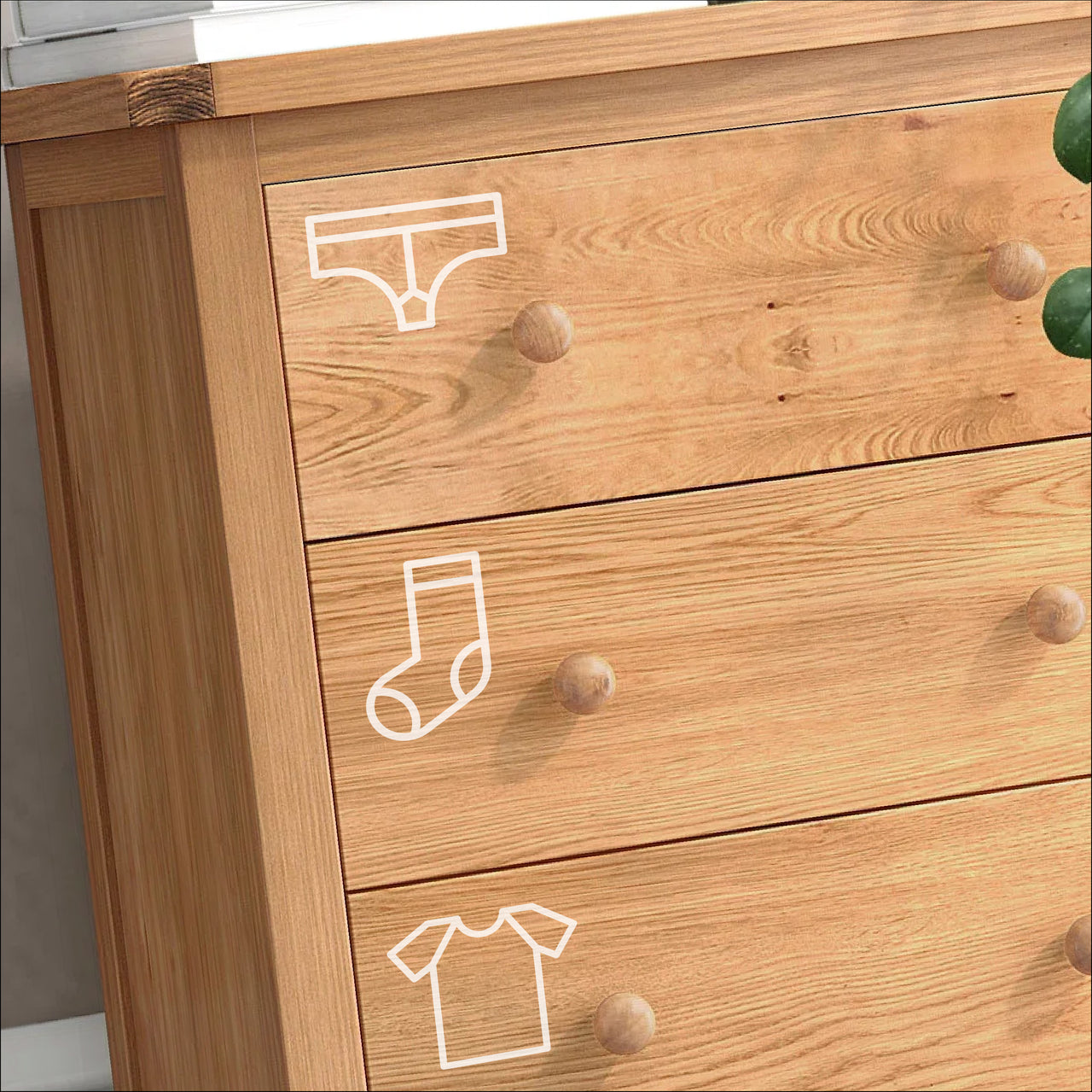A wooden chest of drawers with white bedroom organisation decals stuck on them